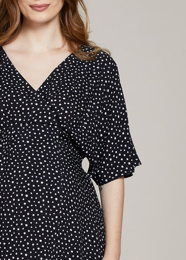 Black dress with white polka dot pattern worn by a person on a neutral background